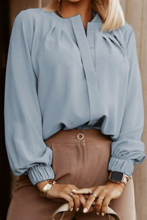 a woman wearing a blue blouse and brown pants