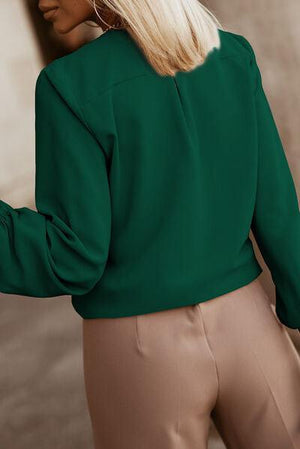 a woman wearing a green blouse and tan pants