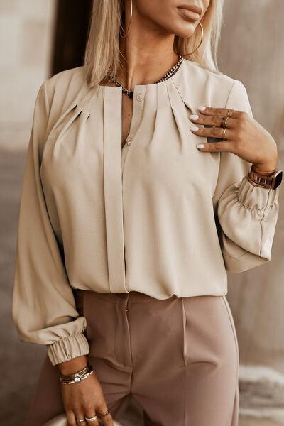 a woman wearing a beige blouse and pants