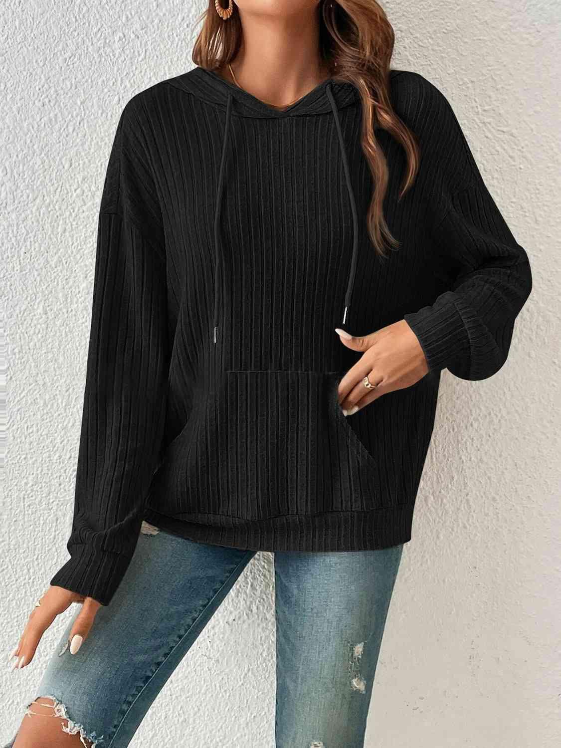 a woman wearing a black sweater and ripped jeans