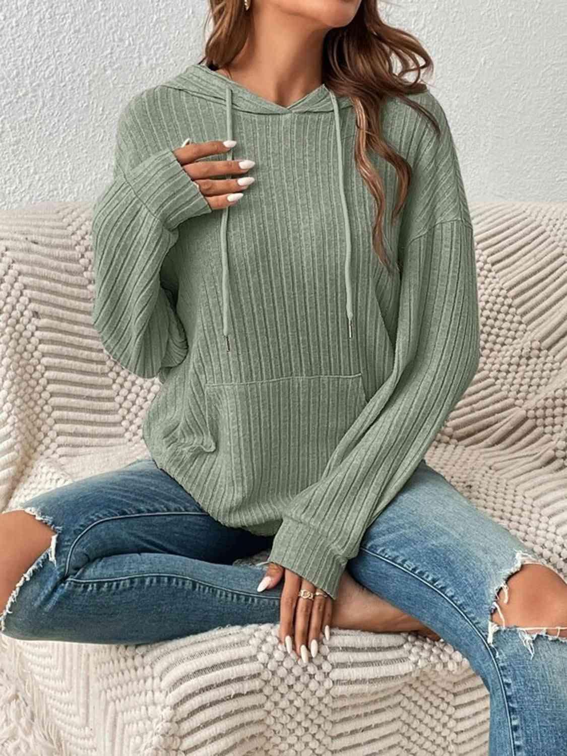 a woman sitting on a couch wearing a green sweater