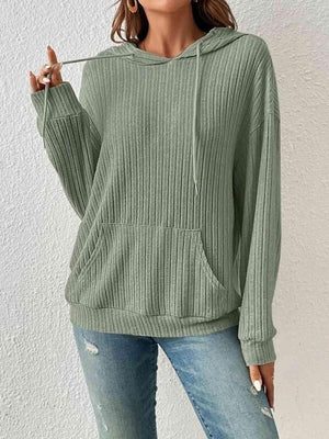 a woman wearing a green sweater and ripped jeans