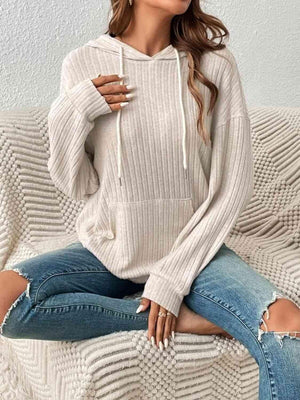 a woman sitting on a couch wearing a white sweater and ripped jeans