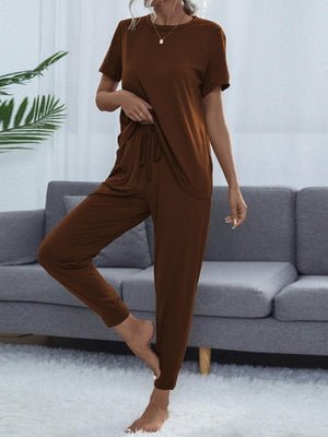 a woman in a brown jumpsuit standing in front of a couch