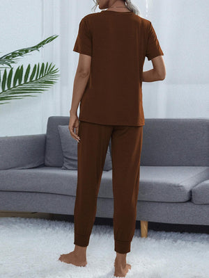 a woman standing in a living room wearing a brown shirt and pants