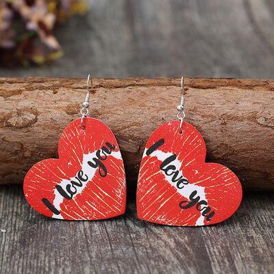 a pair of red heart shaped wooden earrings with words on them