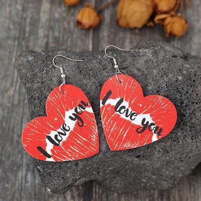 a pair of heart shaped wooden earrings with words on them