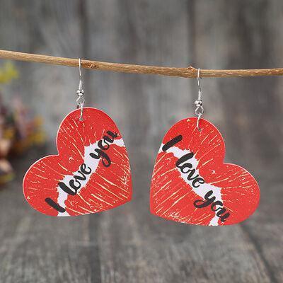 a pair of red heart shaped earrings hanging from a twig