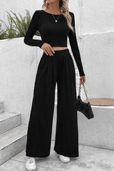 a woman wearing a black crop top and wide legged pants