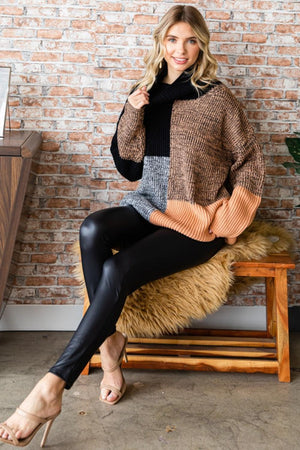 a woman sitting on a bench wearing a sweater and leggings