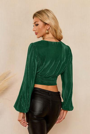 a woman wearing a green top and black pants