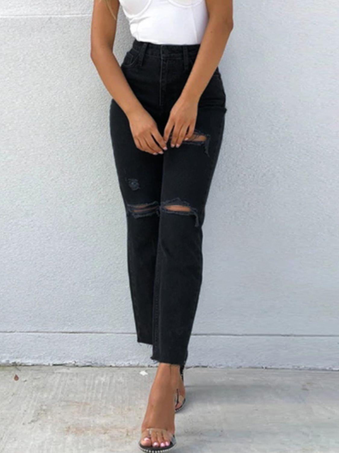 a woman wearing black ripped jeans and a white tank top