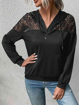 a woman wearing a black top with lace sleeves