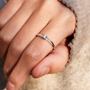 a close up of a person's hand holding a diamond ring