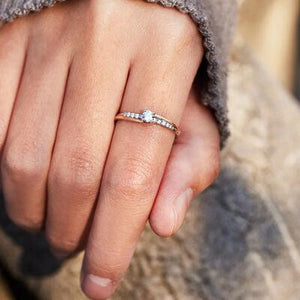 a close up of a person's hand holding a diamond ring