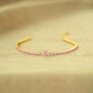 a gold bracelet with pink stones on it