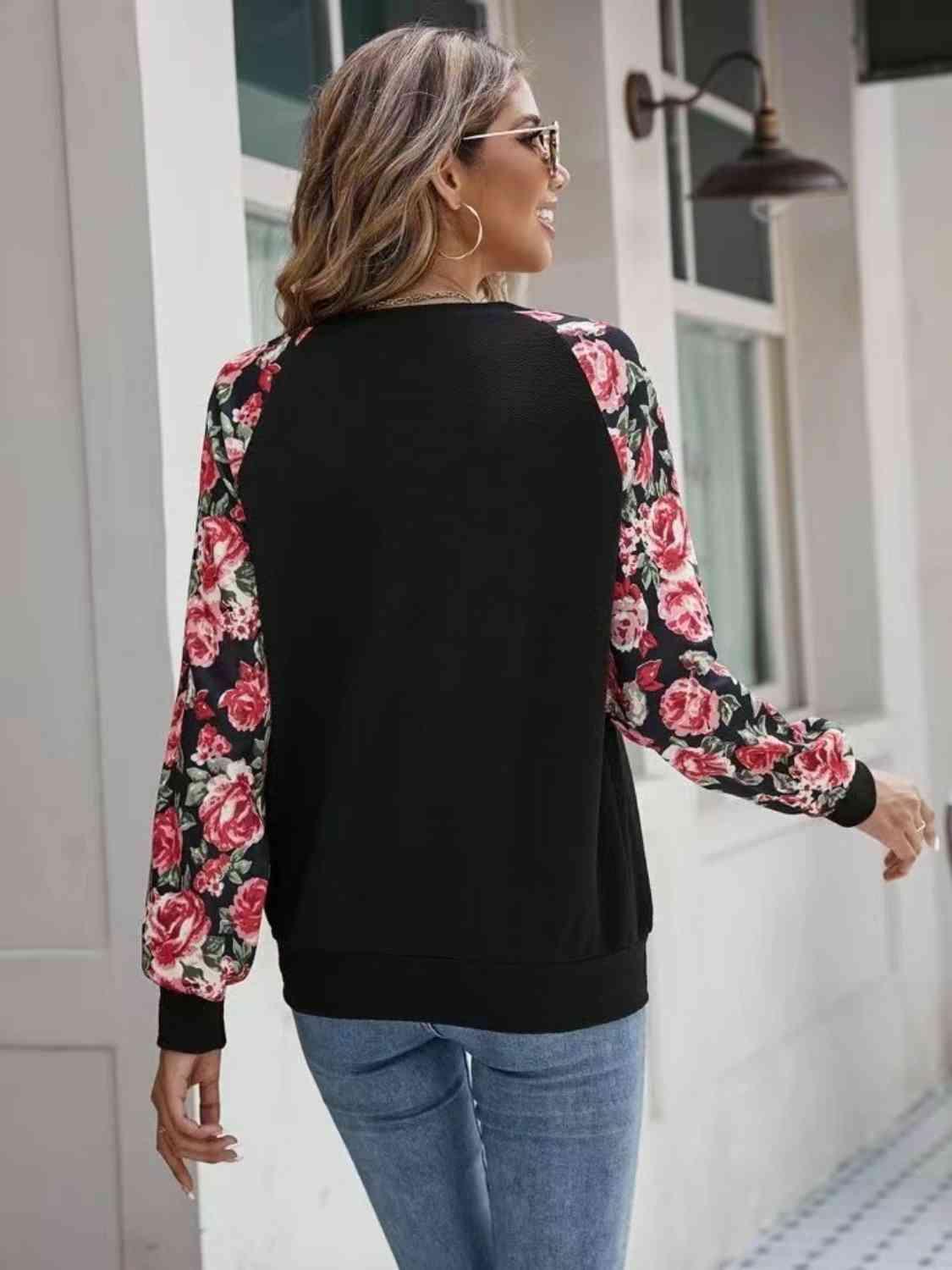 a woman walking down a sidewalk wearing a black and pink floral top
