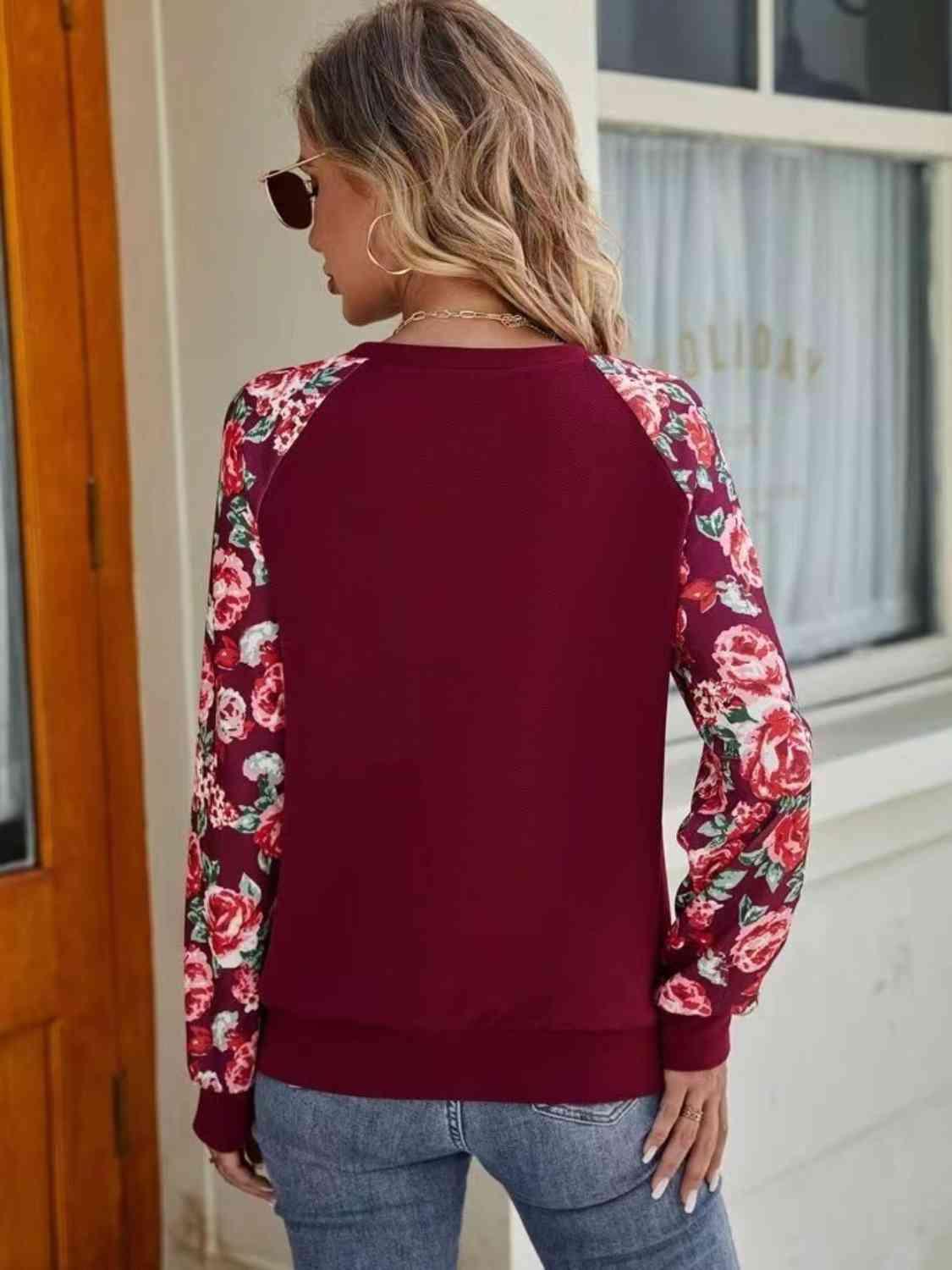 a woman wearing a red sweater with floral sleeves