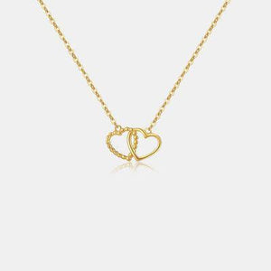 a gold necklace with two intertwined hearts