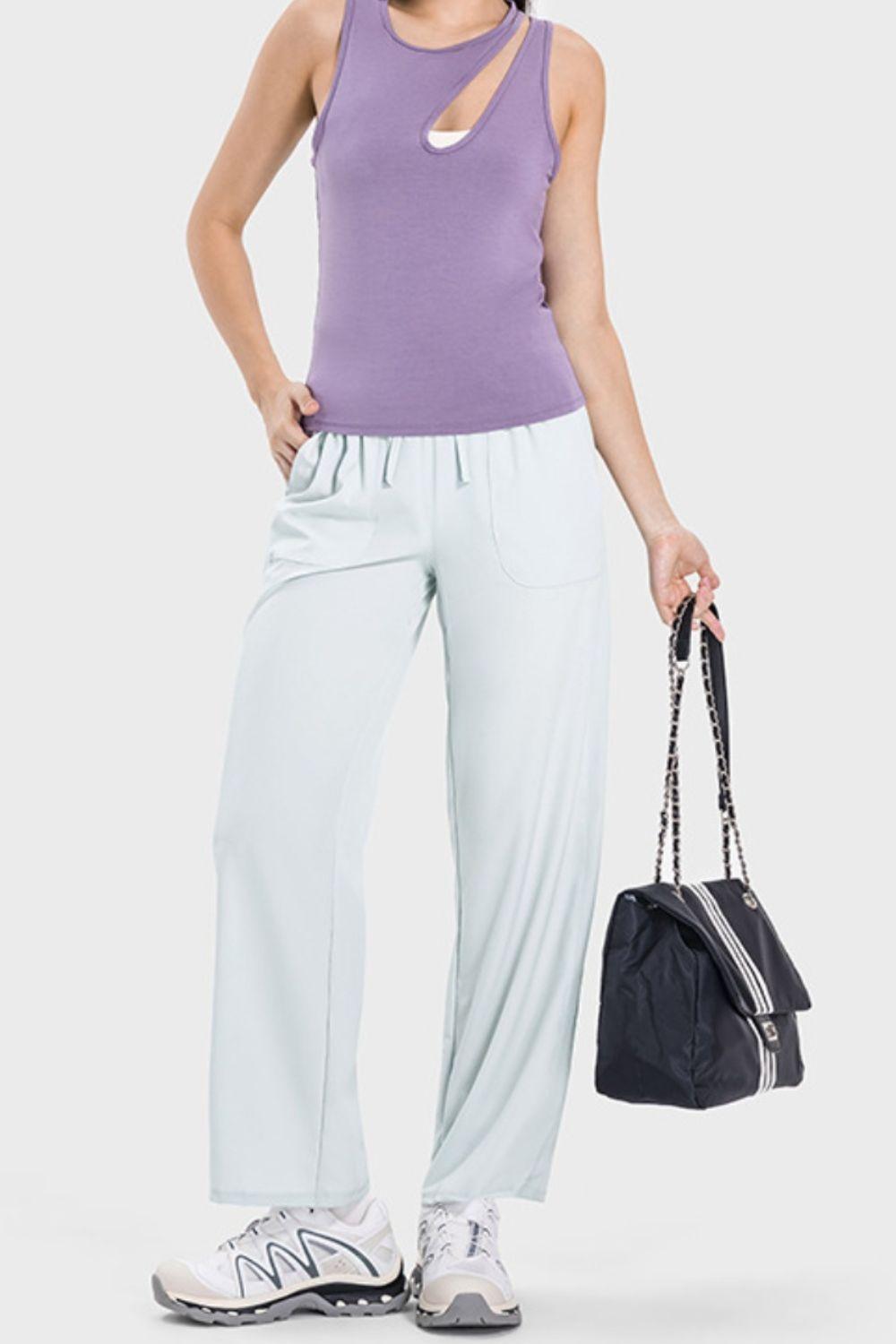 a woman in a purple tank top and white pants