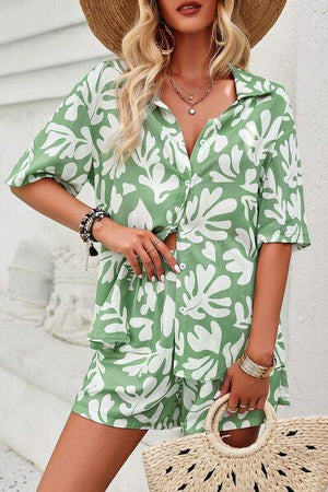 a woman wearing a green and white floral print romper