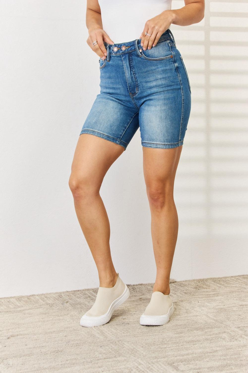 a woman in a white tank top and blue denim shorts