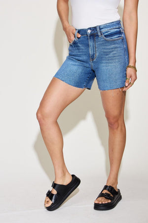 a woman in a white tank top and blue denim shorts