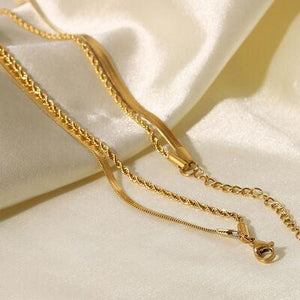a close up of a gold necklace on a white cloth