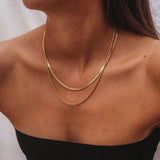 a woman wearing a black dress and a gold necklace
