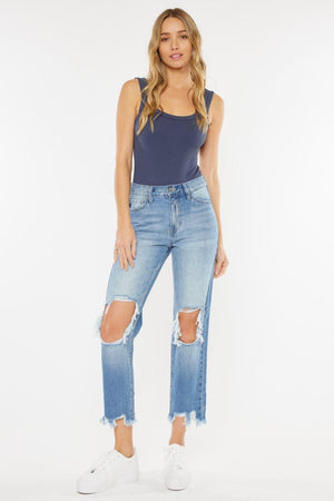 a woman wearing a blue tank top and ripped jeans