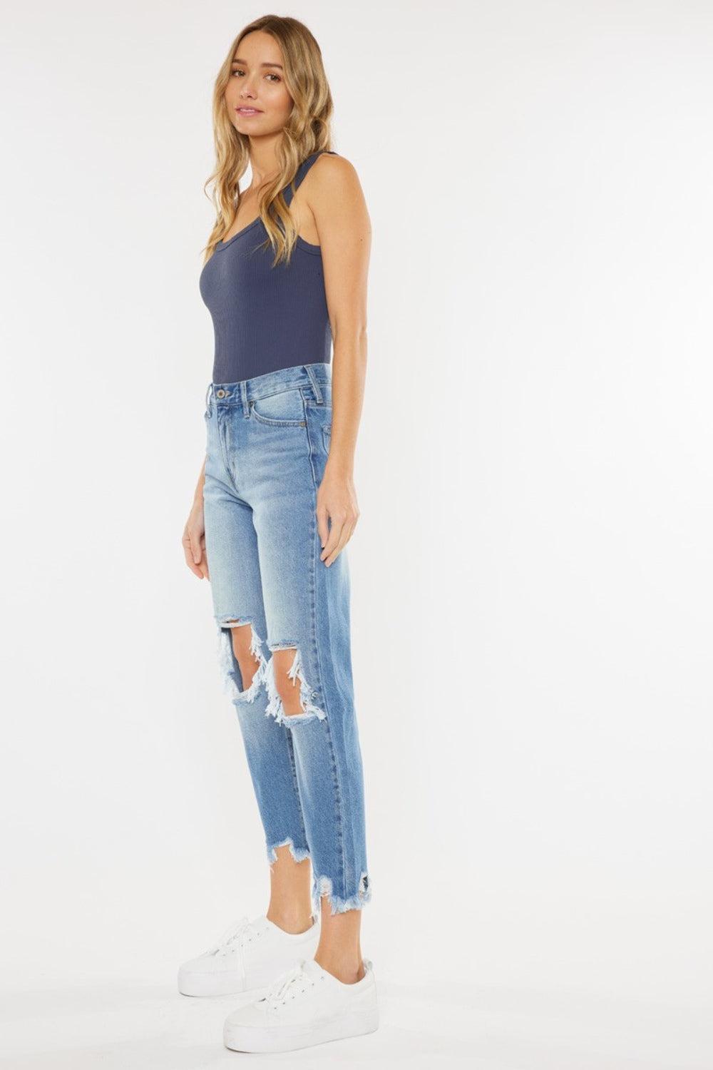 a woman in a tank top and ripped jeans