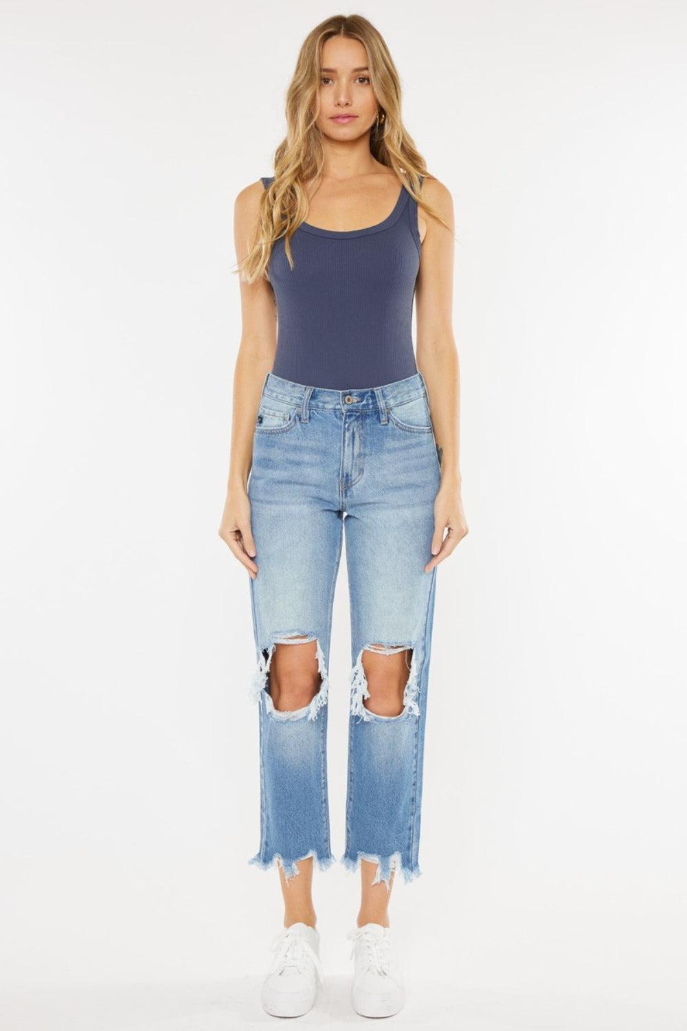 a woman wearing a blue tank top and ripped jeans