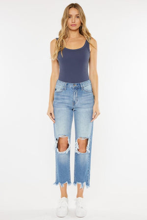 a woman wearing a blue tank top and ripped jeans
