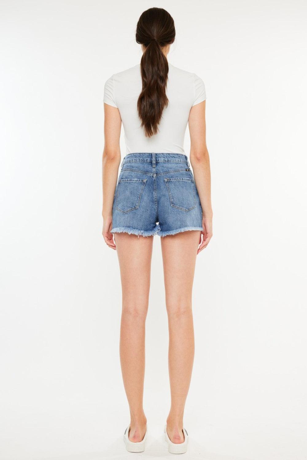a woman in a white shirt and denim shorts