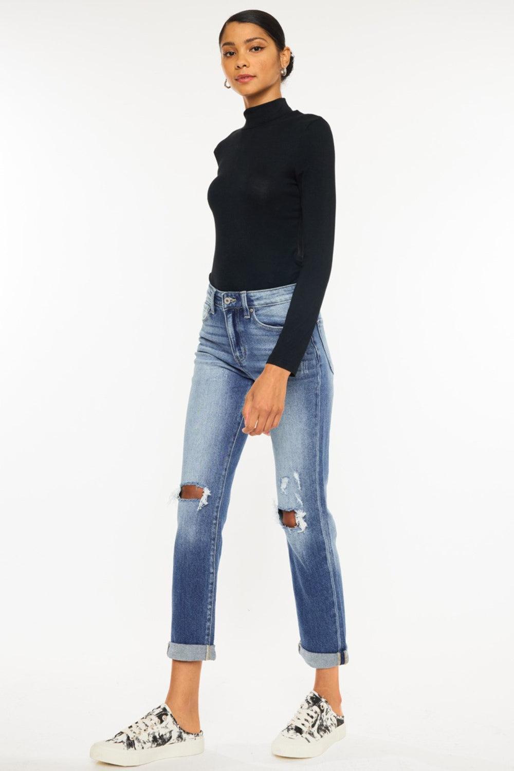 a woman in a black top and ripped jeans