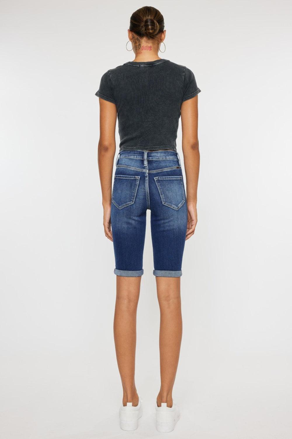the back of a woman in a black shirt and jeans shorts