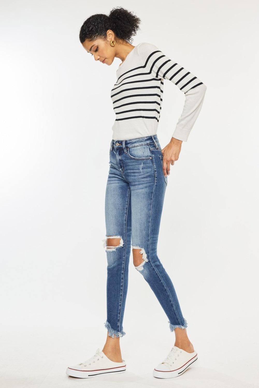 a woman wearing ripped jeans and a striped sweater