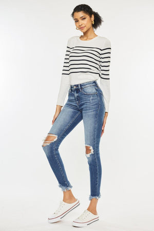 a woman wearing ripped jeans and a striped sweater