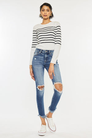 a woman wearing ripped jeans and a striped sweater