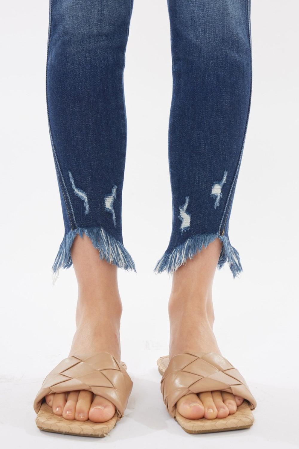 a woman's legs with ripped jeans and sandals