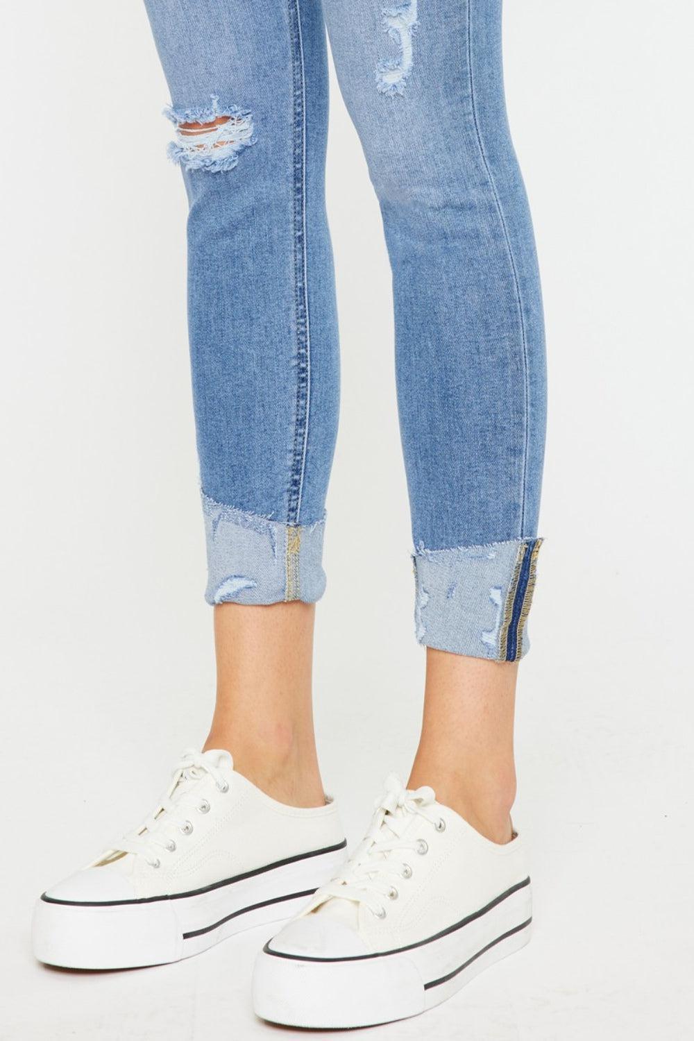 a woman wearing ripped jeans and white sneakers