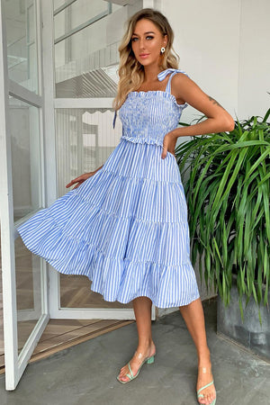 a woman posing in a blue and white striped dress