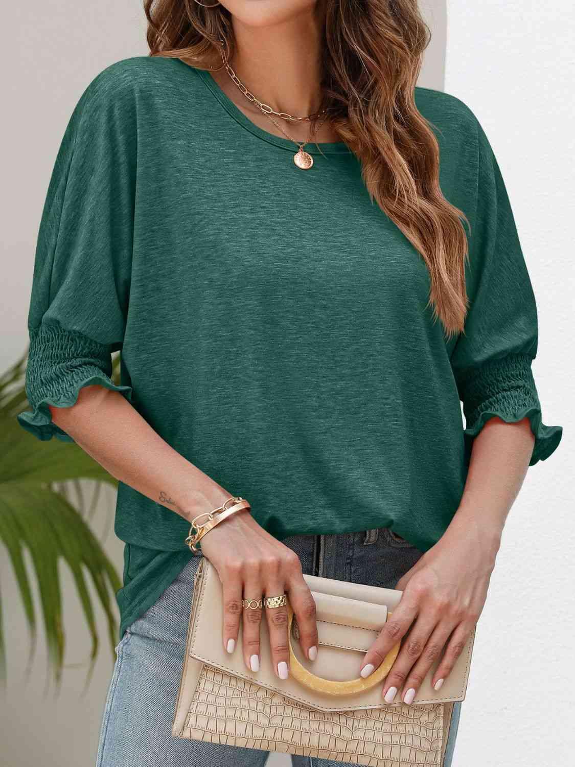 a woman wearing a green top and jeans