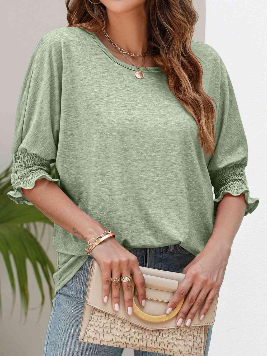 a woman wearing a green top and jeans