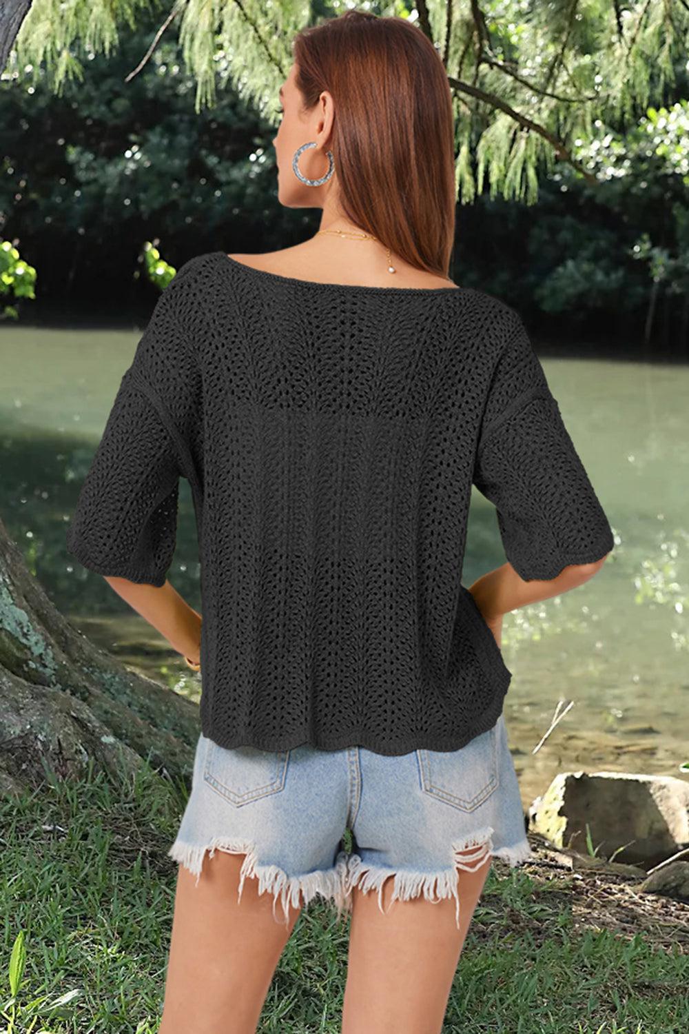 a woman standing next to a river wearing a black sweater