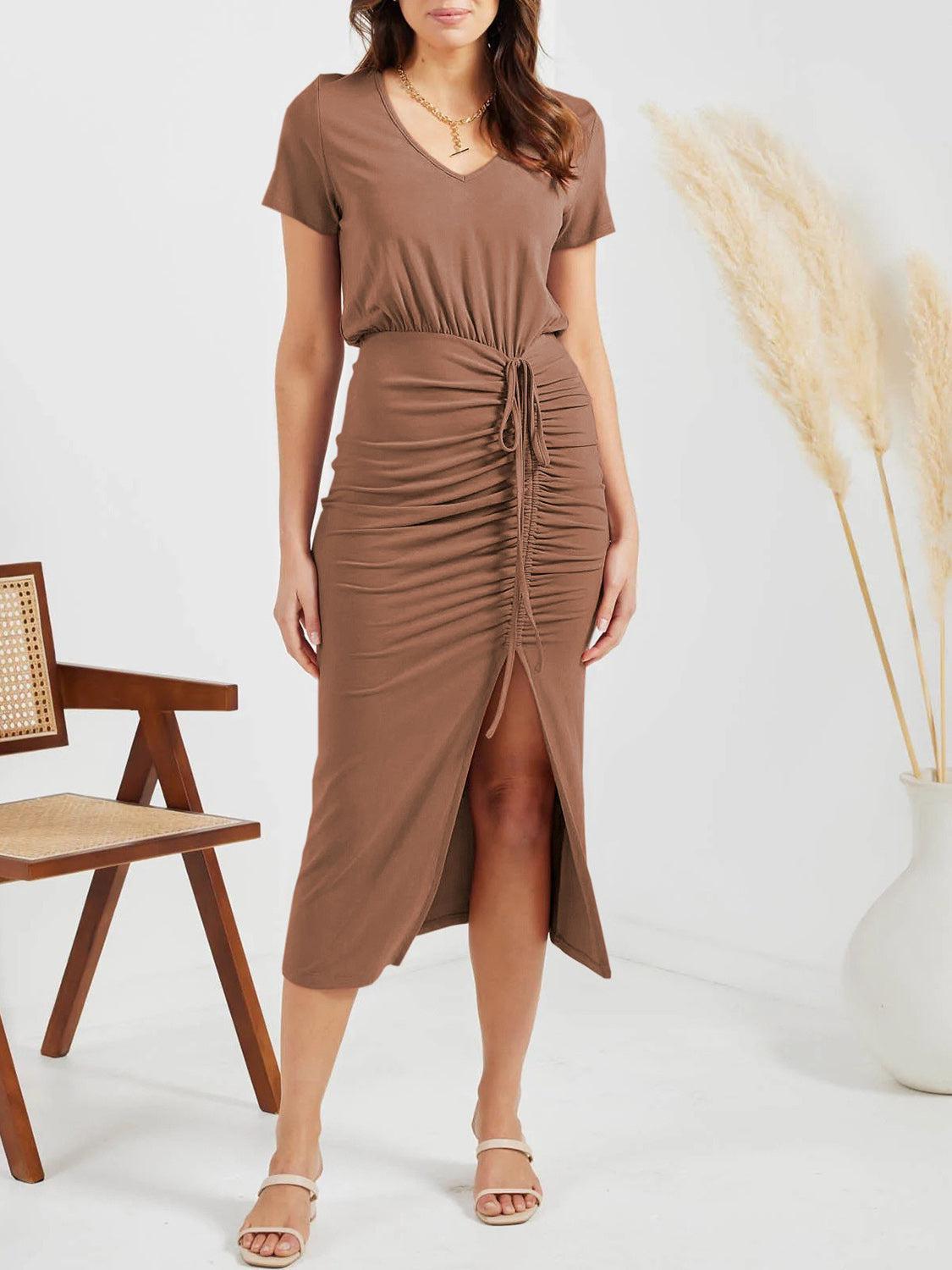 a woman standing in front of a chair wearing a brown dress