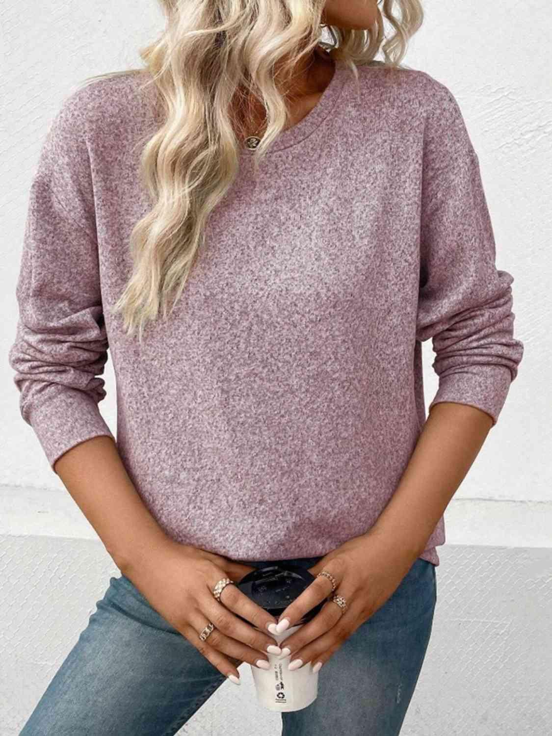 a woman wearing a pink sweater and jeans