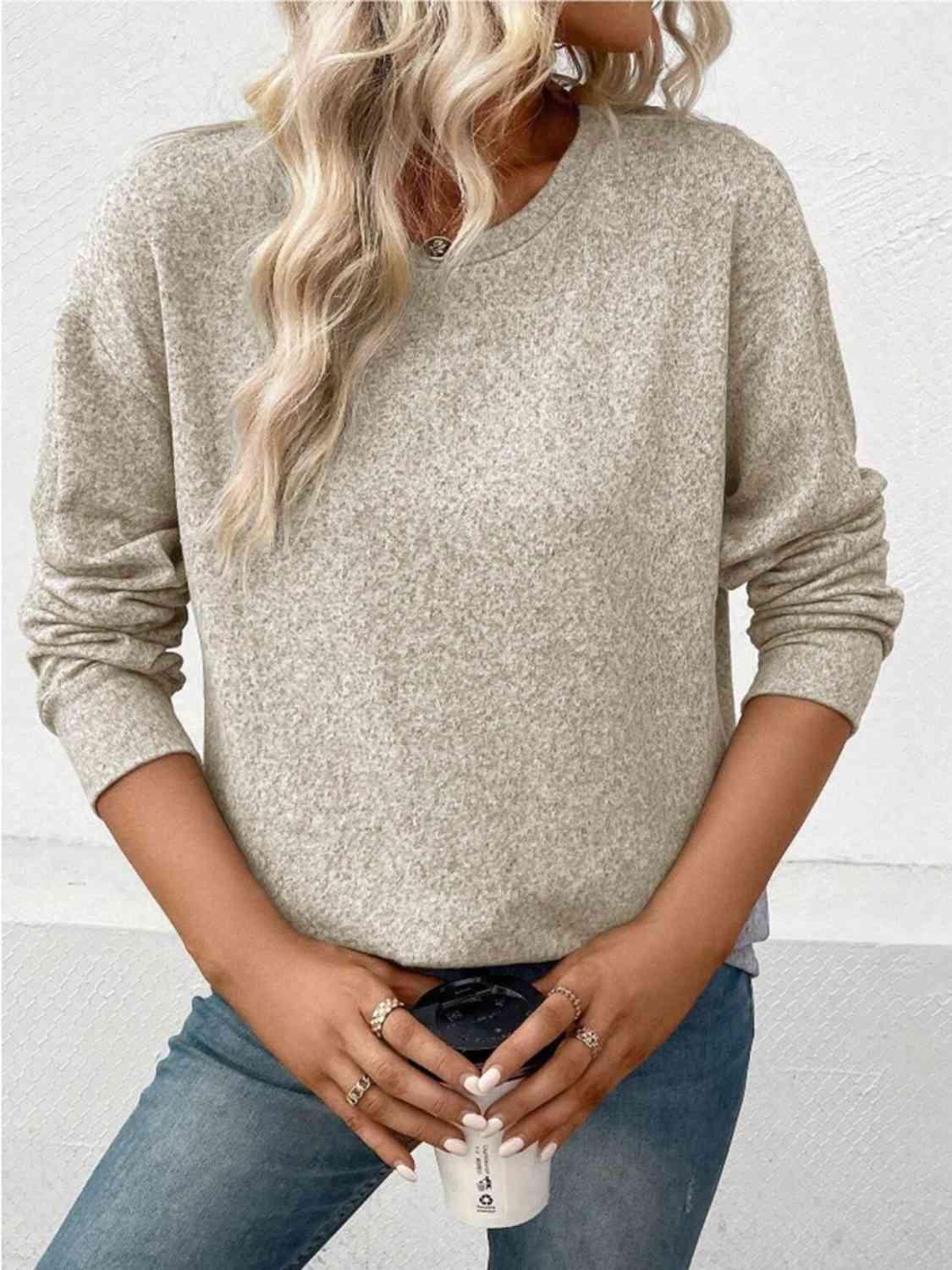 a woman wearing a beige sweater and jeans