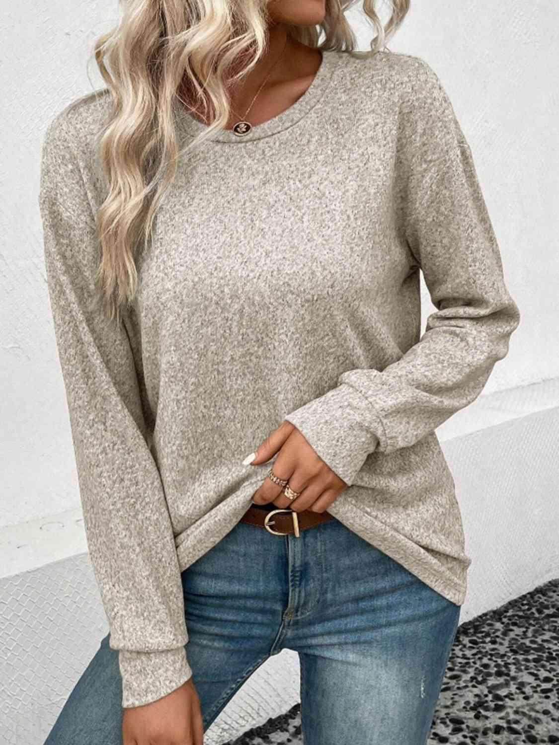 a woman wearing a grey sweater and jeans