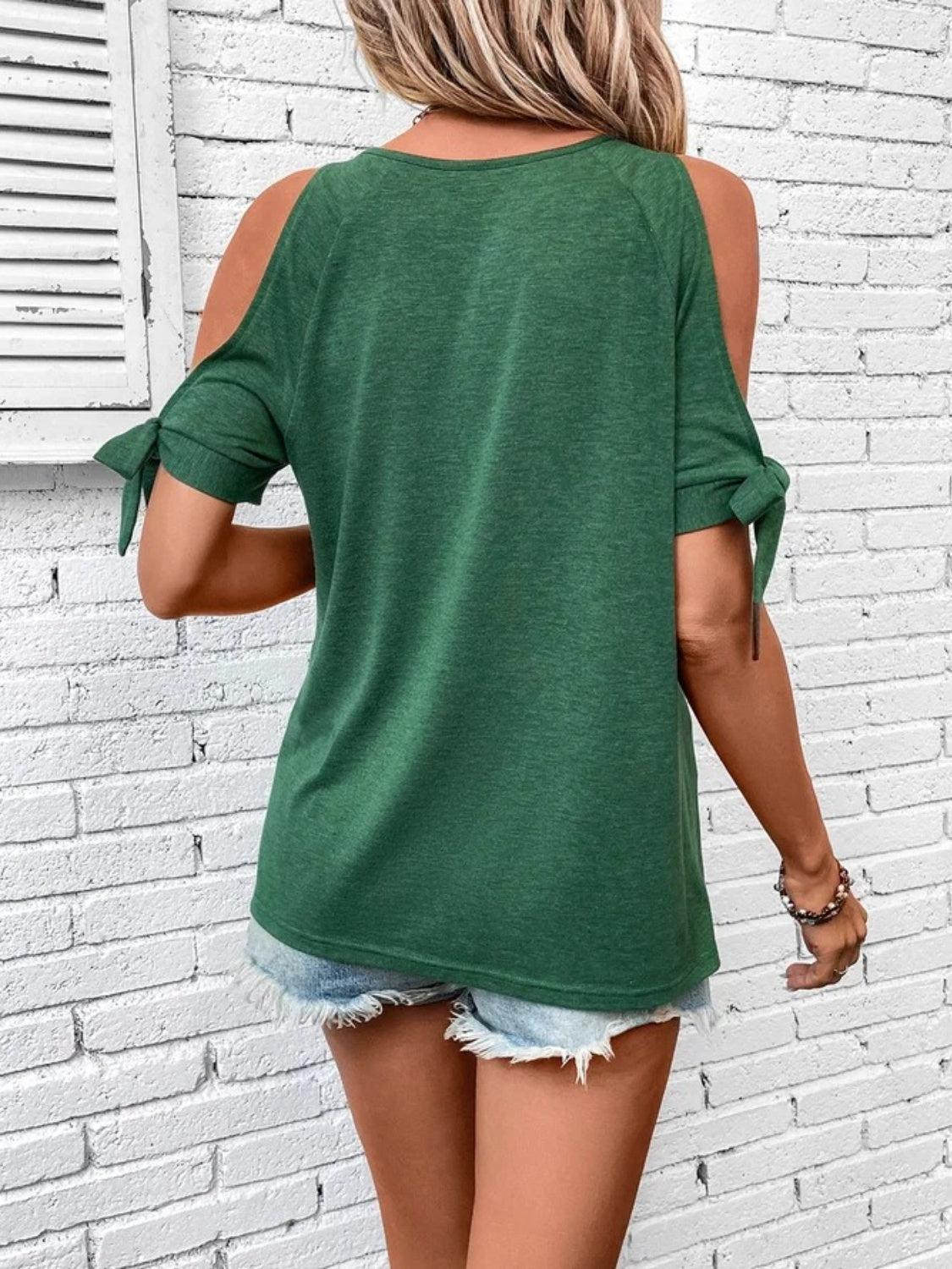 a woman wearing a green top and ripped shorts